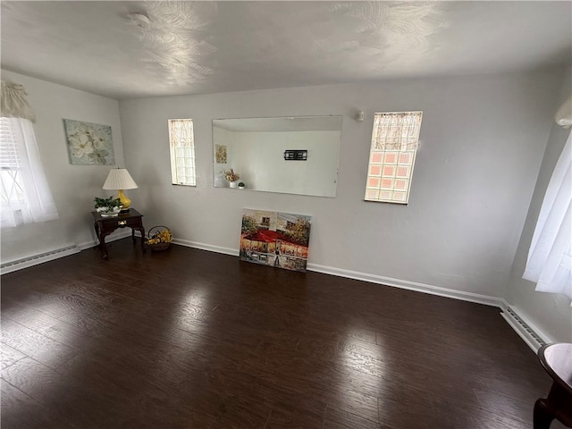 interior space featuring plenty of natural light, dark wood-type flooring, and a baseboard heating unit