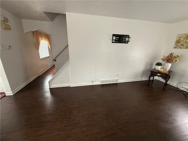 spare room with dark hardwood / wood-style flooring and a baseboard radiator