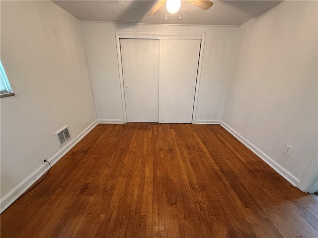 unfurnished bedroom featuring a closet, ceiling fan, hardwood / wood-style floors, and a textured ceiling