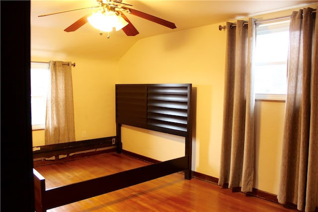 unfurnished bedroom with ceiling fan, wood-type flooring, and lofted ceiling