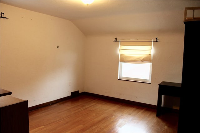 empty room with hardwood / wood-style floors and lofted ceiling