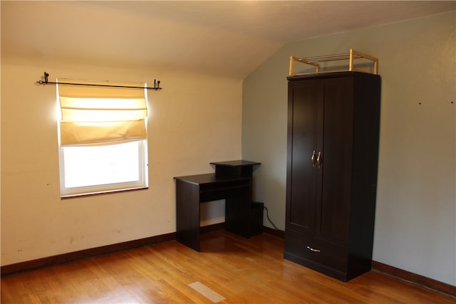 empty room with vaulted ceiling and light hardwood / wood-style flooring