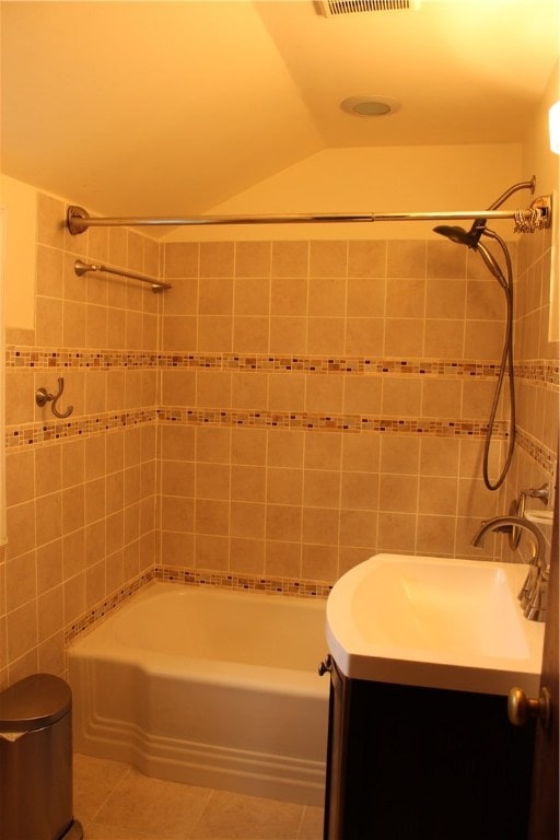 bathroom featuring tile patterned floors, vanity, lofted ceiling, and tiled shower / bath