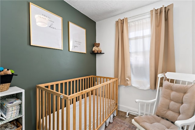 carpeted bedroom featuring a nursery area and a textured ceiling