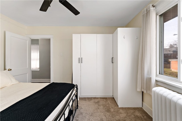 carpeted bedroom featuring radiator, ceiling fan, and multiple windows