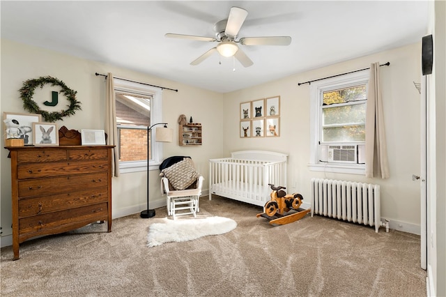 carpeted bedroom with ceiling fan, cooling unit, a crib, and radiator