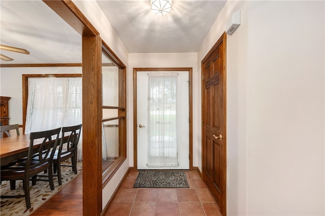 doorway featuring tile patterned floors, a wealth of natural light, and crown molding