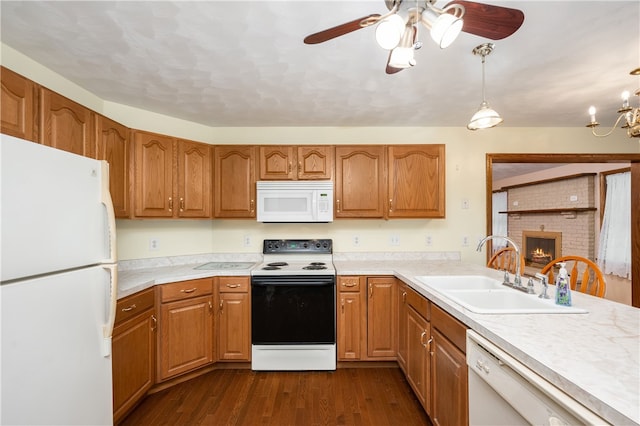 kitchen with ceiling fan with notable chandelier, white appliances, sink, decorative light fixtures, and dark hardwood / wood-style floors