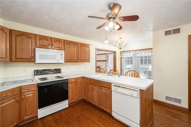 kitchen with white appliances, dark wood-type flooring, ceiling fan with notable chandelier, sink, and kitchen peninsula