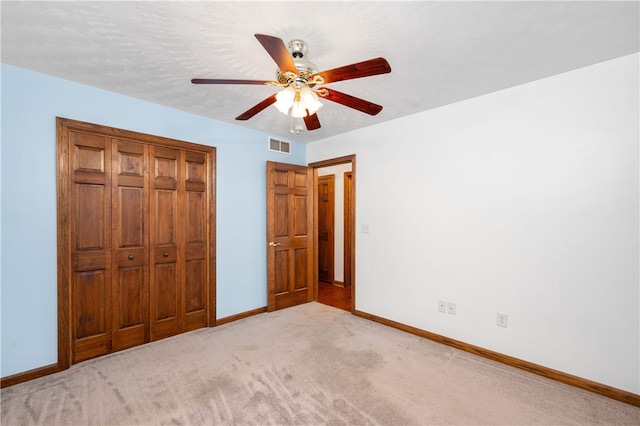 unfurnished bedroom with ceiling fan, light colored carpet, and a closet