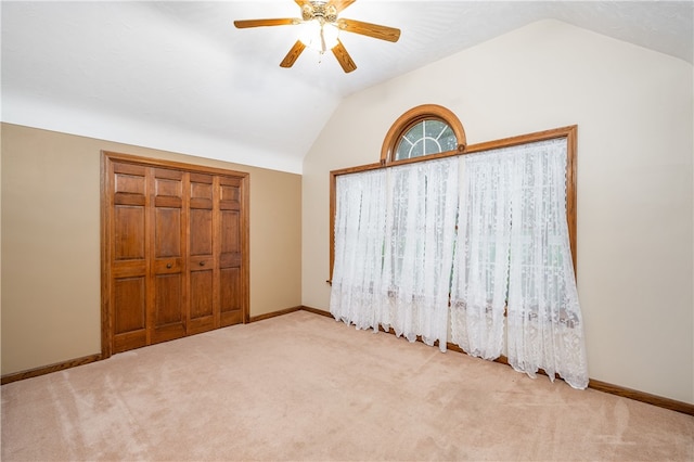 unfurnished bedroom featuring ceiling fan, a closet, light carpet, and vaulted ceiling