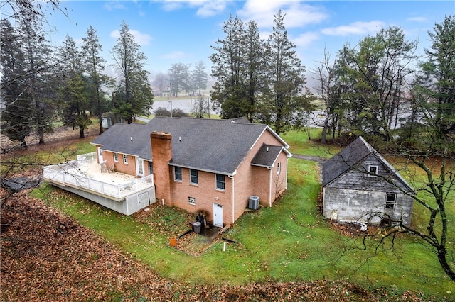 rear view of property with central AC unit and a lawn