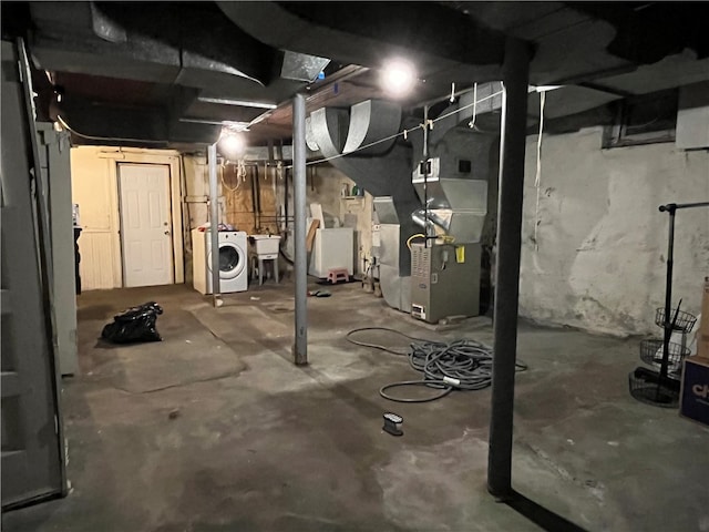 basement featuring heating unit, sink, and washer / dryer