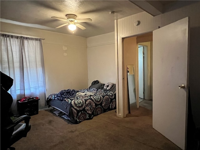 carpeted bedroom with beamed ceiling and ceiling fan