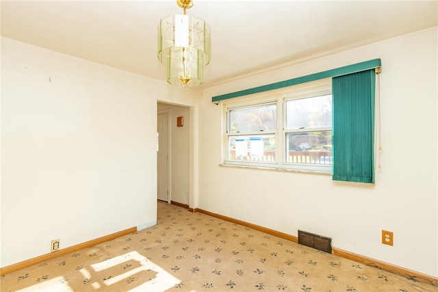 unfurnished room featuring a chandelier