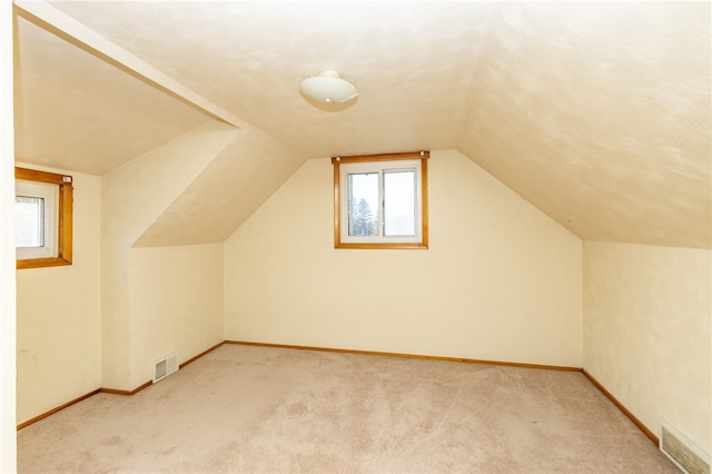 bonus room with light colored carpet and vaulted ceiling