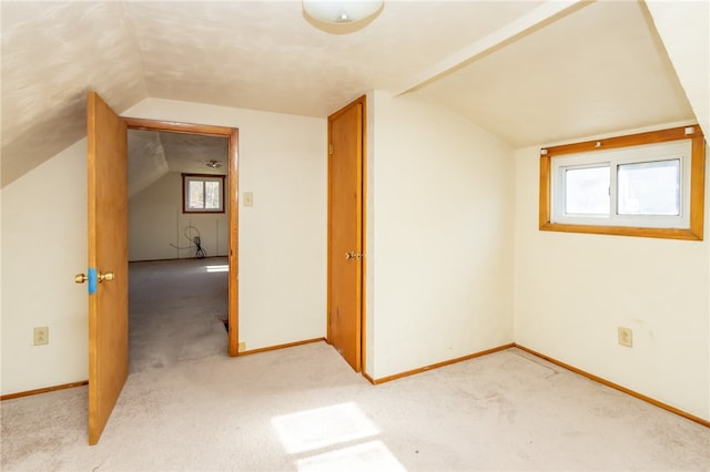 bonus room with a wealth of natural light, light carpet, and vaulted ceiling