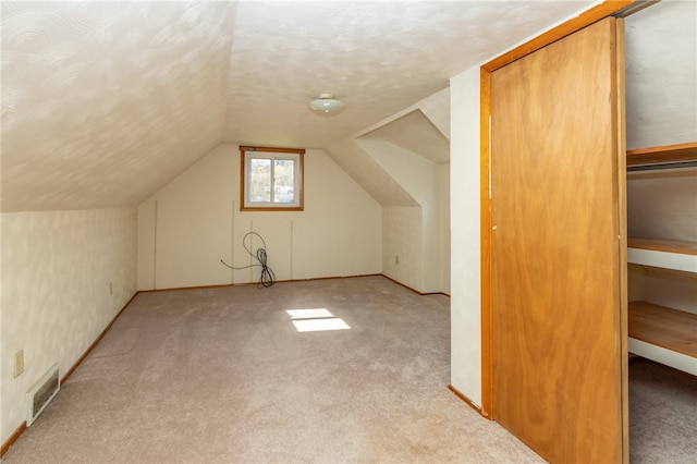 bonus room with lofted ceiling and light carpet