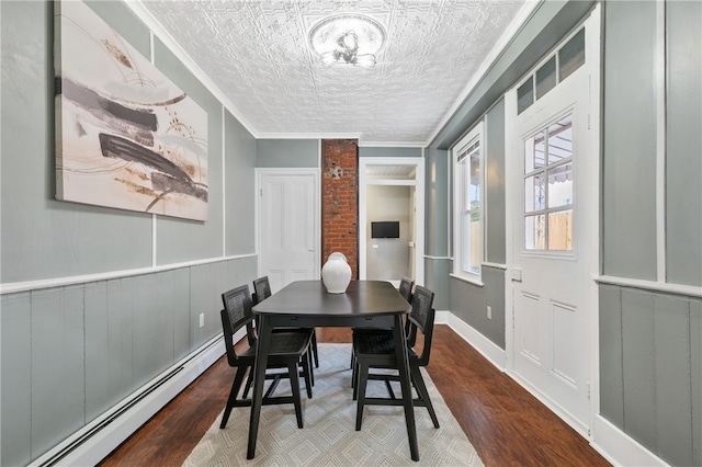 dining area with hardwood / wood-style flooring, ornamental molding, a textured ceiling, and a baseboard heating unit