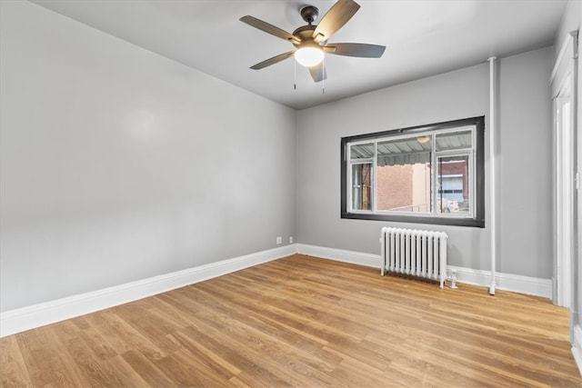 empty room featuring ceiling fan, radiator heating unit, and light hardwood / wood-style flooring