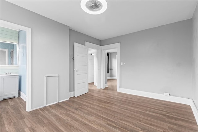 unfurnished bedroom featuring ensuite bathroom and wood-type flooring