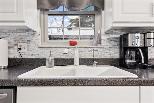 kitchen with backsplash, white cabinetry, and sink