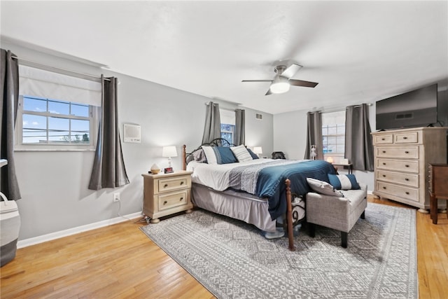 bedroom featuring ceiling fan, light hardwood / wood-style flooring, and multiple windows