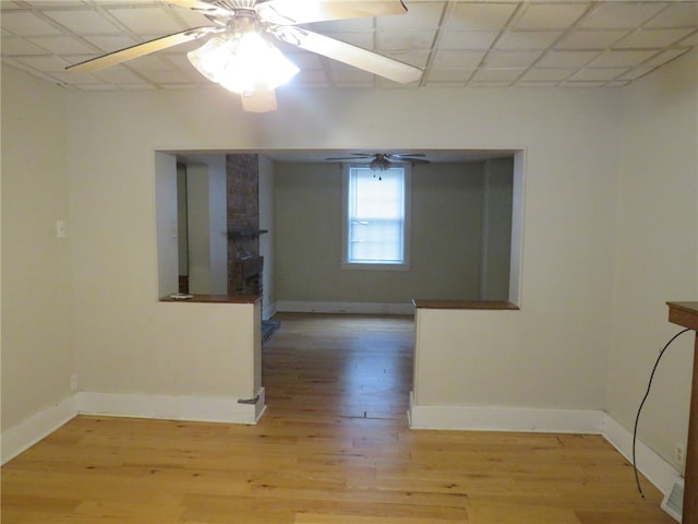 empty room featuring a paneled ceiling, ceiling fan, and light hardwood / wood-style flooring