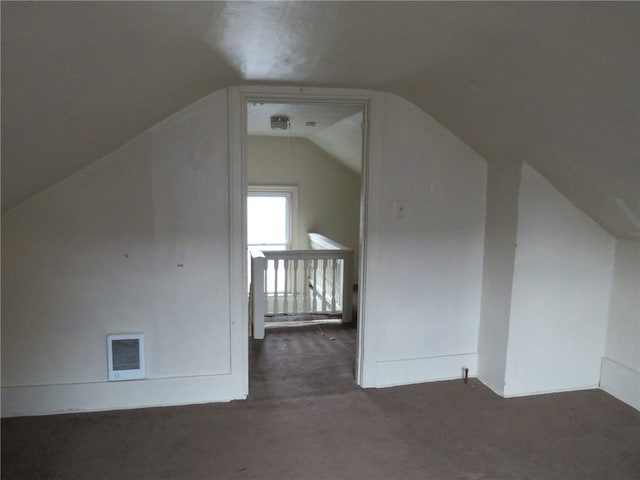 additional living space with dark colored carpet and vaulted ceiling