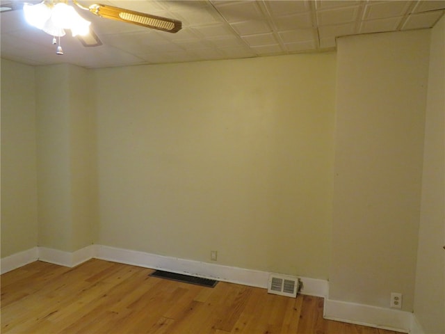 empty room featuring ceiling fan, a drop ceiling, and wood-type flooring