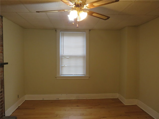 unfurnished room featuring a brick fireplace, light hardwood / wood-style flooring, and ceiling fan