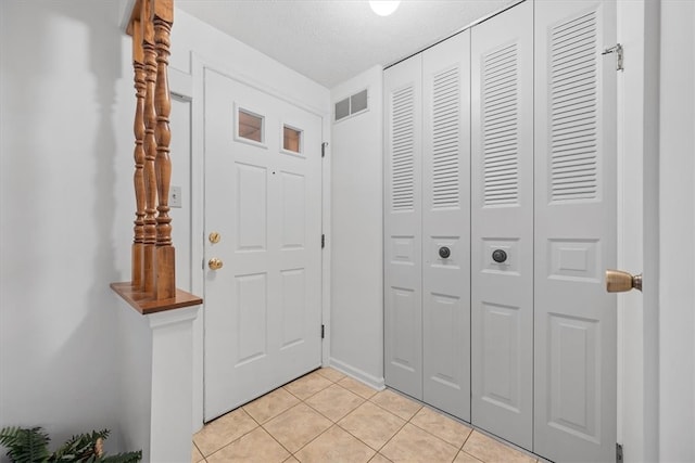 entryway with a textured ceiling and light tile patterned floors