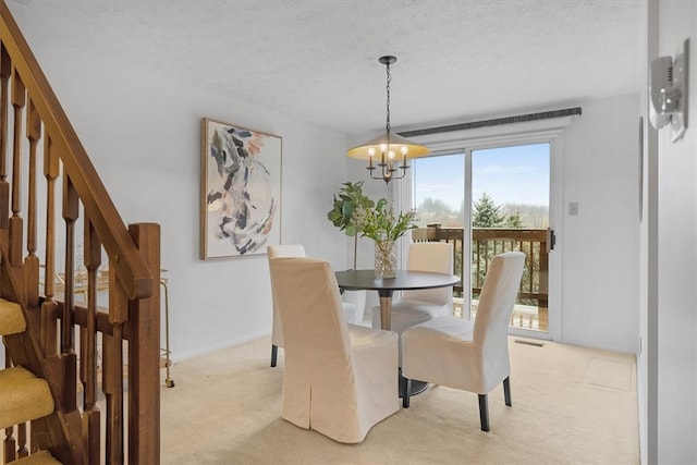 dining space featuring an inviting chandelier, light carpet, and a textured ceiling