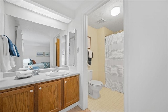 bathroom with a textured ceiling, vanity, and toilet