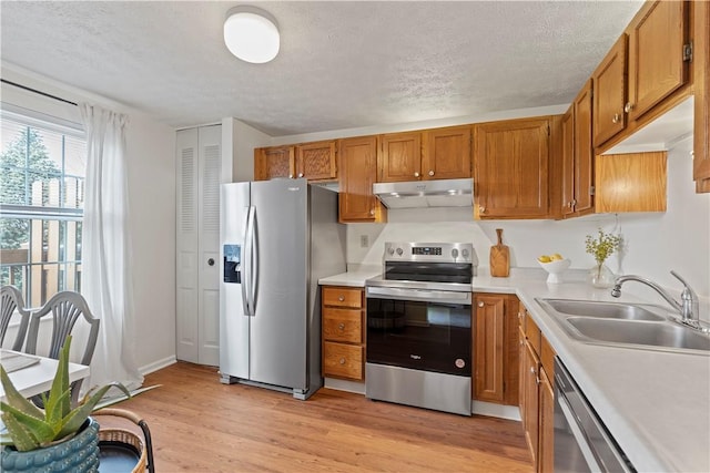 kitchen with appliances with stainless steel finishes, light hardwood / wood-style flooring, a textured ceiling, and sink