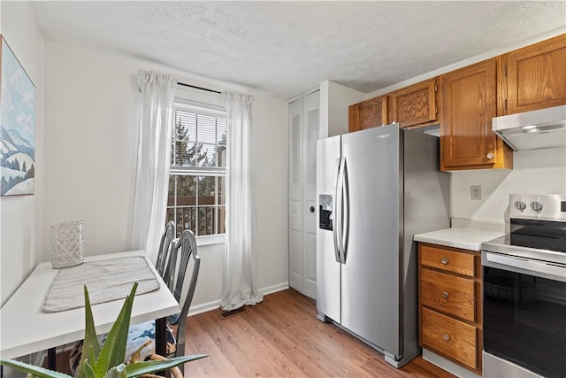 kitchen featuring light wood-type flooring, appliances with stainless steel finishes, and a textured ceiling