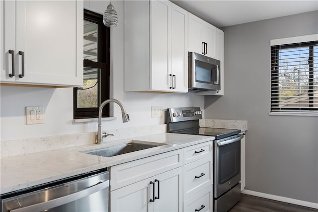 kitchen featuring stainless steel appliances, white cabinetry, plenty of natural light, and sink