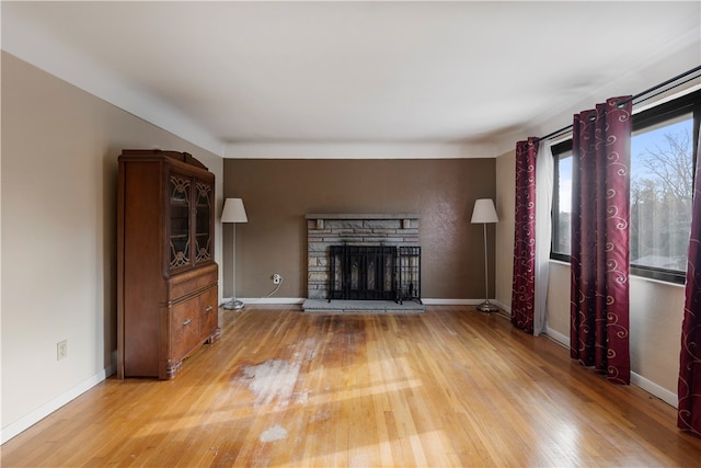 unfurnished living room featuring hardwood / wood-style floors and a stone fireplace