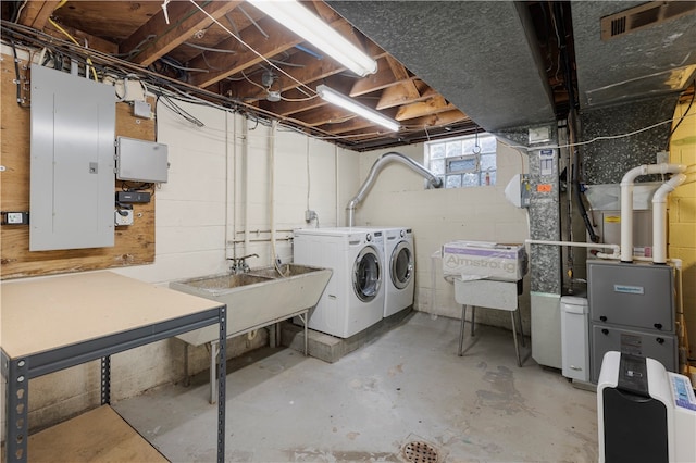 basement featuring independent washer and dryer, electric panel, heating unit, and sink