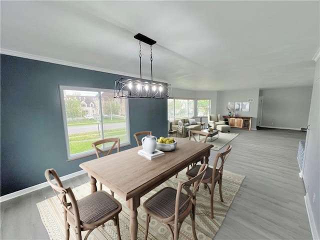 dining area featuring light wood-type flooring, crown molding, and an inviting chandelier