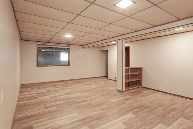 basement featuring a drop ceiling and light hardwood / wood-style floors