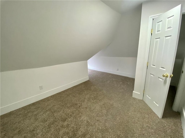 additional living space featuring dark carpet and vaulted ceiling