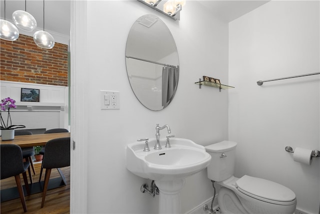 bathroom featuring hardwood / wood-style floors, a shower with shower curtain, toilet, and brick wall