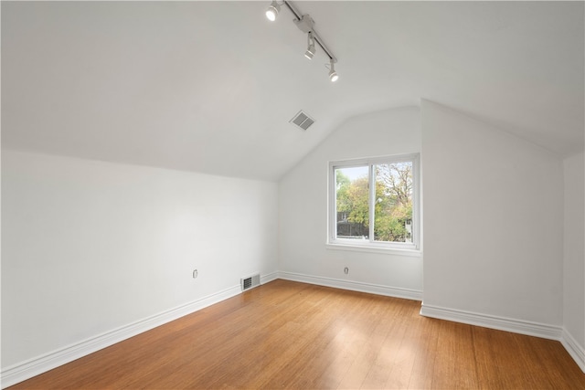 additional living space with vaulted ceiling and light hardwood / wood-style flooring