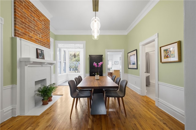 dining area with a fireplace, wood-type flooring, and ornamental molding