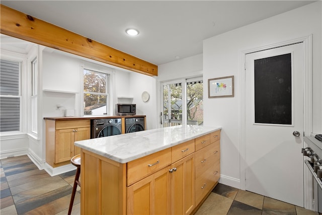 kitchen featuring a kitchen bar, washing machine and dryer, a wealth of natural light, and kitchen peninsula