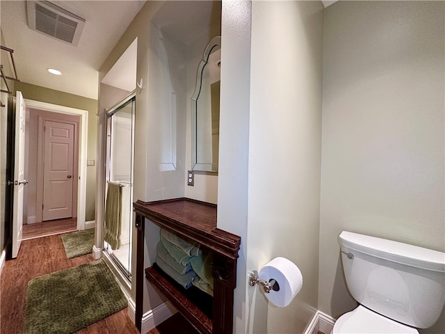 bathroom featuring hardwood / wood-style flooring, toilet, and a shower with door