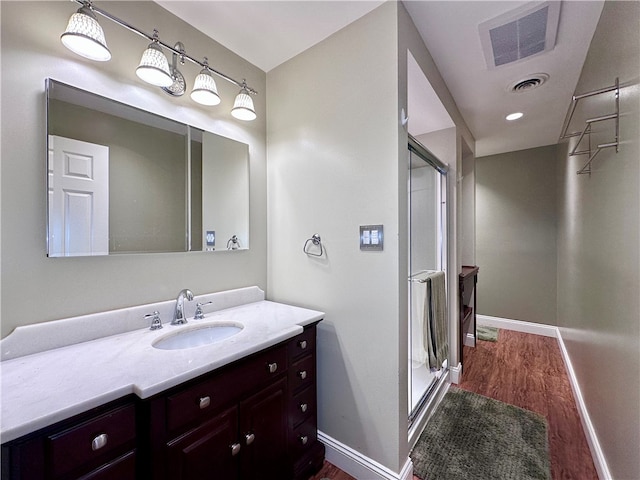 bathroom with hardwood / wood-style floors, vanity, and a shower with shower door