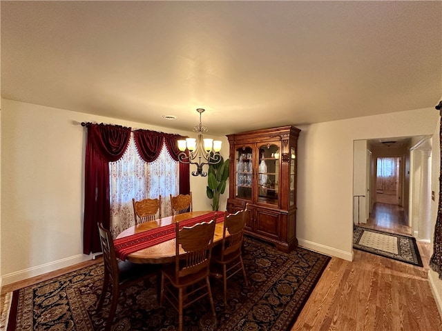 dining area featuring dark wood-type flooring and a notable chandelier