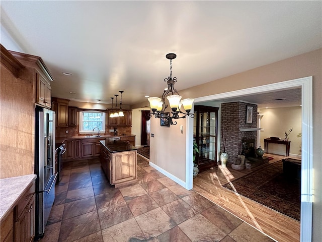 kitchen with an inviting chandelier, sink, a brick fireplace, decorative light fixtures, and high end fridge